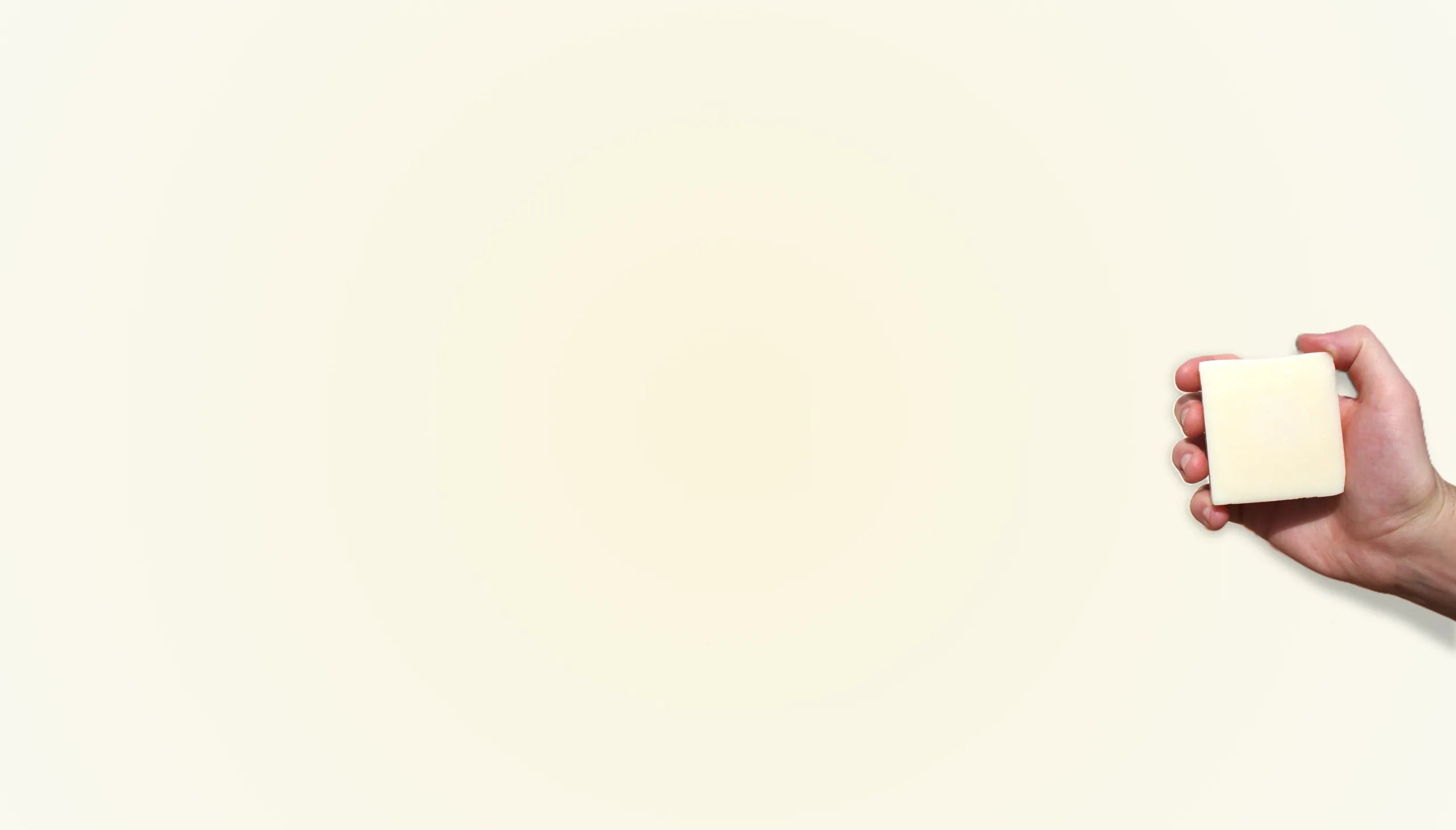 Hand holding a small white object against a beige background