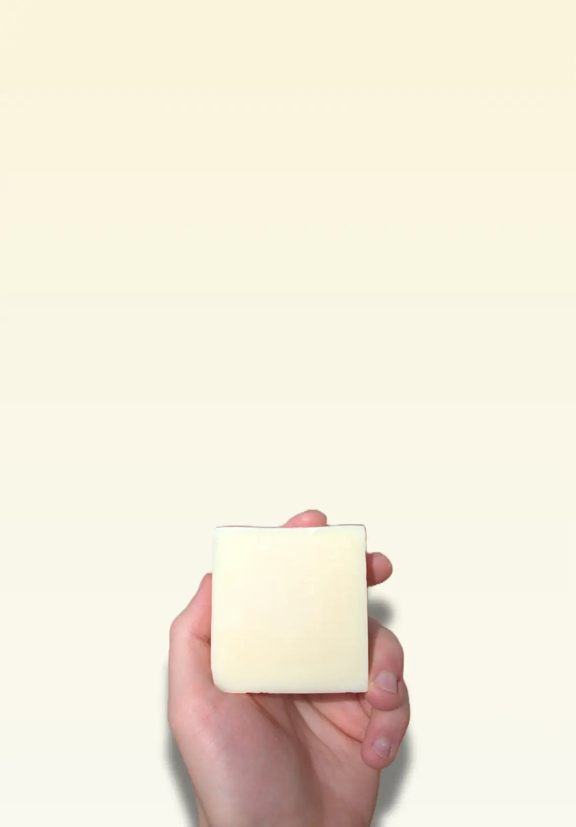 Hand holding a small white candle against a light beige background